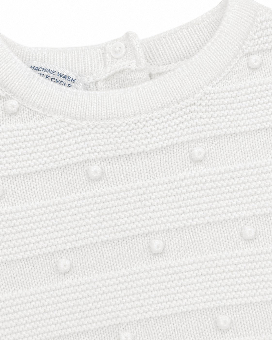 Carriage Boutique white knit baby bris outfit featuring textured pom-pom details and a button-back closure.