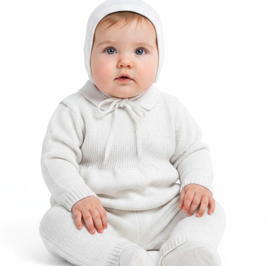 Carriage Boutique white knit baby boy baptism outfit with matching bonnet and collared sweater on a seated infant