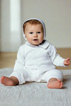 Baby boy wearing a white Carriage Boutique knit cotton christening outfit with a matching bonnet and knitted collar.