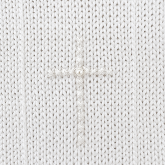 Close-up of Carriage Boutique white knit cotton christening outfit featuring an embroidered cross with a center pearl.