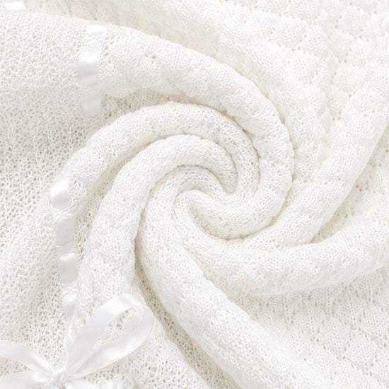 Carriage Boutique white baby blanket featuring soft knit texture, delicate Belgium lace, and a satin ribbon bow.