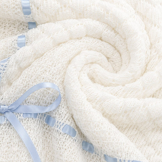 Carriage Boutique white baby blanket with intricate knit texture and delicate blue ribbon trim.