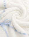 Carriage Boutique white baby blanket with intricate knit texture and delicate blue ribbon trim.