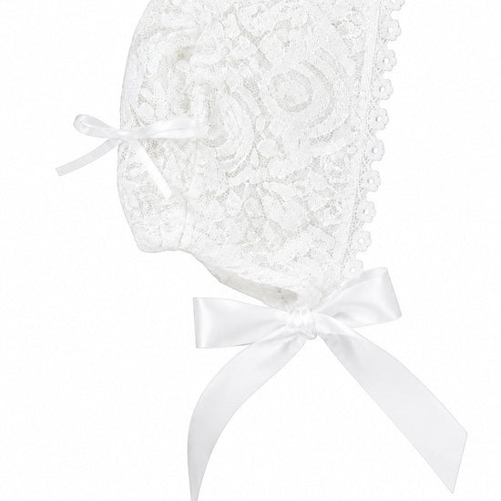 Carriage Boutique white lace baby baptism bonnet with delicate floral patterns and satin ribbon ties.
