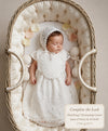 Carriage Boutique white lace christening bib worn by a sleeping baby in a wicker bassinet with a matching bonnet