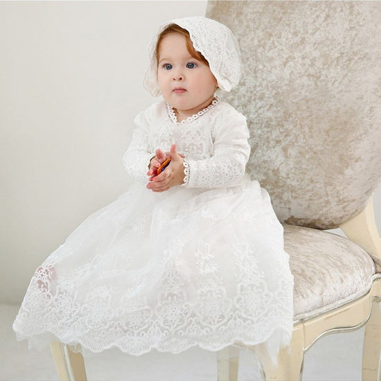 Carriage Boutique white lace christening gown with long sleeves, scalloped hem, and matching bonnet on a baby girl.