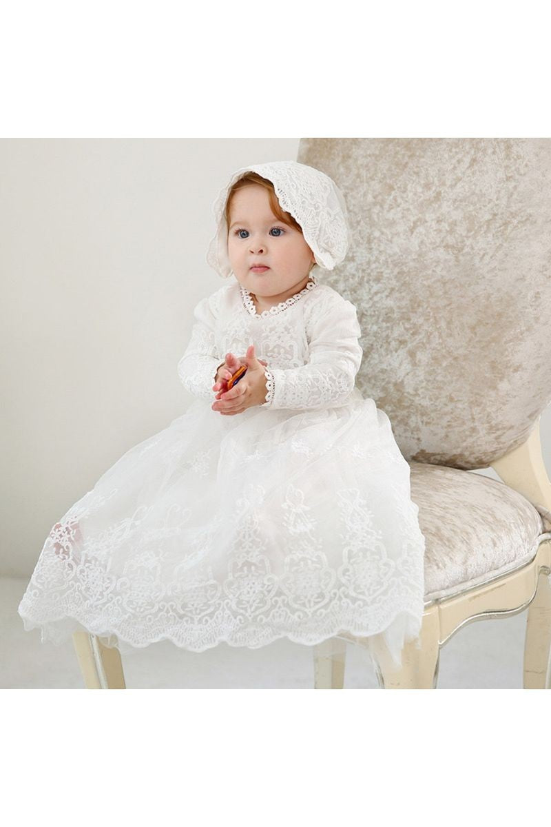 Carriage Boutique white lace christening gown with long sleeves, scalloped hem, and matching bonnet on a baby girl.