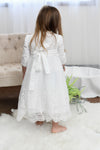 Carriage Boutique white long sleeve lace christening gown with scalloped hem and back bow detail on a young girl