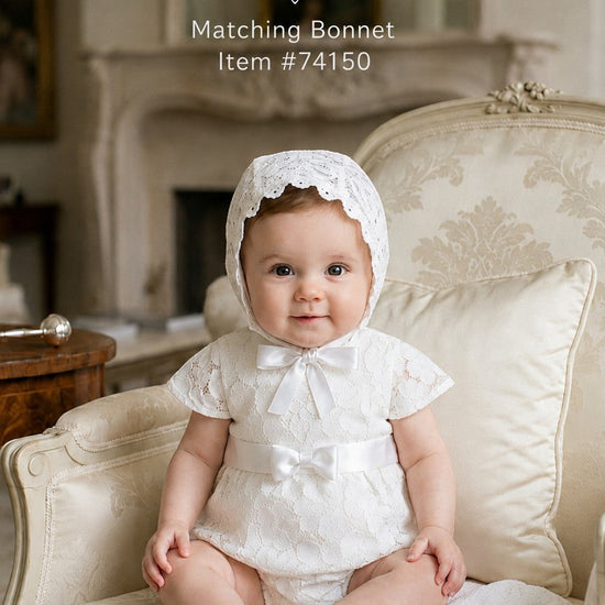 Carriage Boutique baby girl white lace christening bubble romper with matching bonnet sitting in a vintage chair