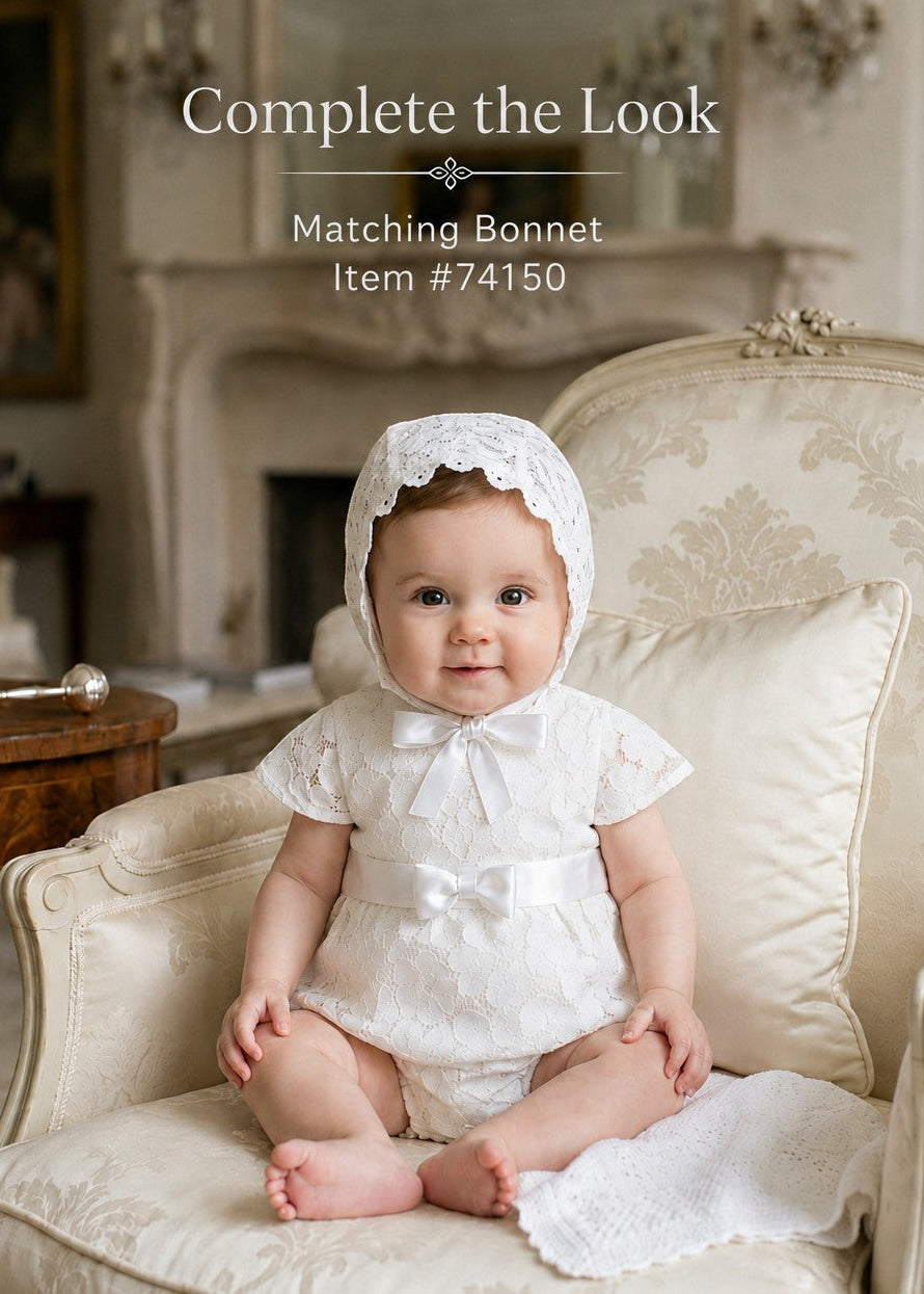 Carriage Boutique baby girl white lace christening bubble romper with matching bonnet sitting in a vintage chair