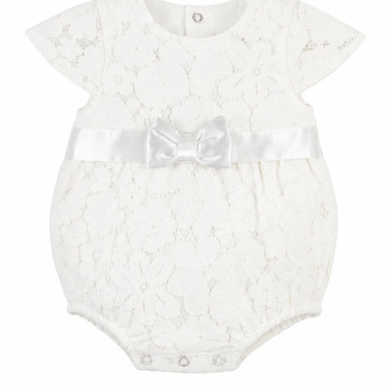 Carriage Boutique white lace baby girl christening bubble romper with a satin waist ribbon and bow detail.