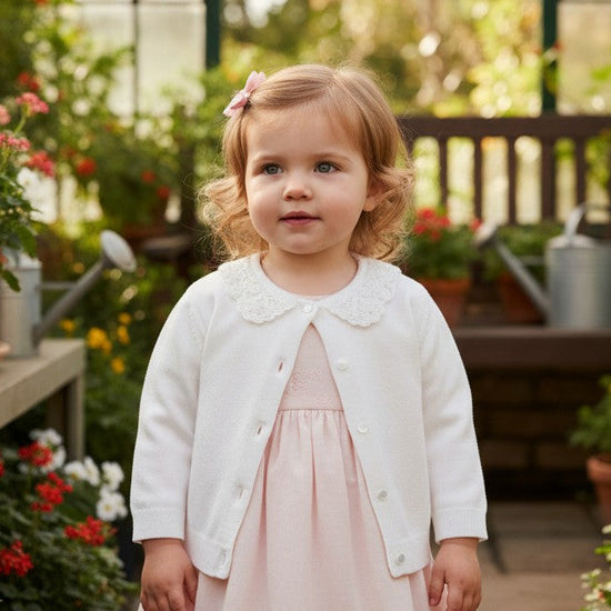 Carriage Boutique white cotton cardigan for girls featuring a delicate lace collar, worn over a soft pink dress.