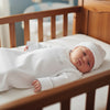 Carriage Boutique white newborn sleep sack with matching hat and monogrammed name, featuring elegant scalloped trim.