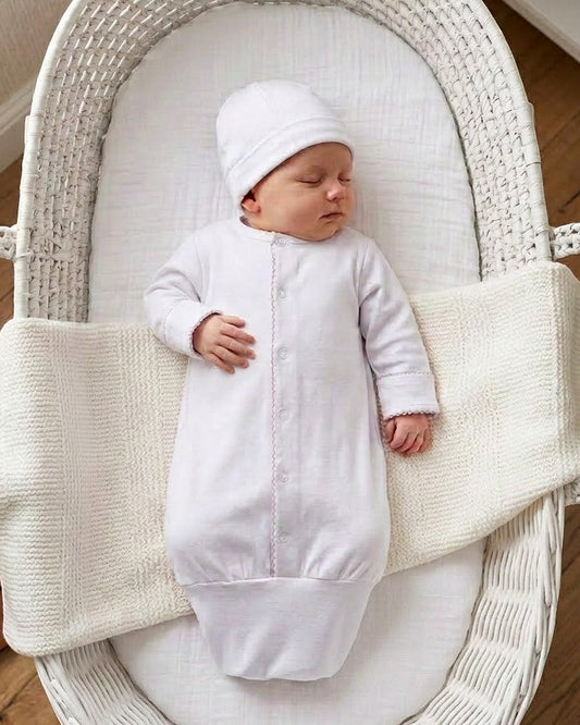 Carriage Boutique white newborn sleep sack and matching hat with scalloped trim on a baby sleeping in a white bassinet