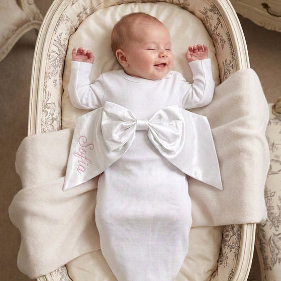 Carriage Boutique newborn baby swaddle gown in white cotton with a large decorative bow and personalized embroidery