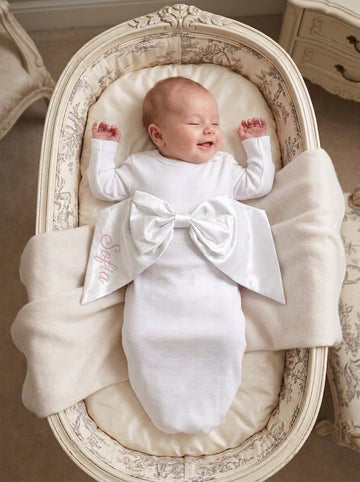 Carriage Boutique newborn baby swaddle gown in white cotton with a large decorative bow and personalized embroidery