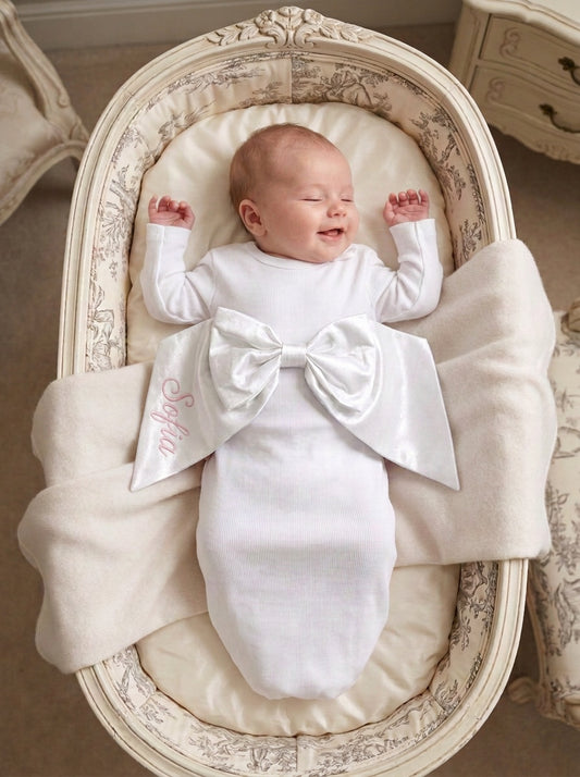 Carriage Boutique newborn baby swaddle gown in white cotton with a large decorative bow and personalized embroidery