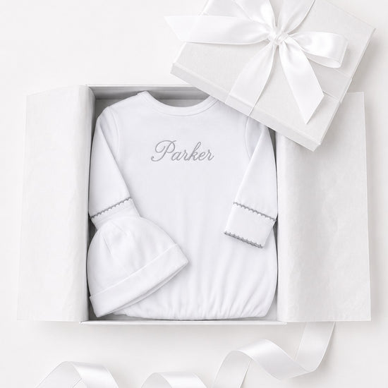 Carriage Boutique white newborn sleep sack and matching hat with personalized embroidery in a gift box.