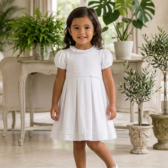 Carriage Boutique white pique toddler girl dress with puff sleeves and ruffled collar in a bright living room
