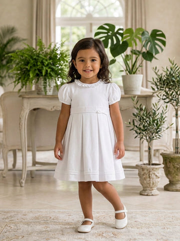 Carriage Boutique white pique toddler girl dress with puff sleeves and ruffled collar in a bright living room