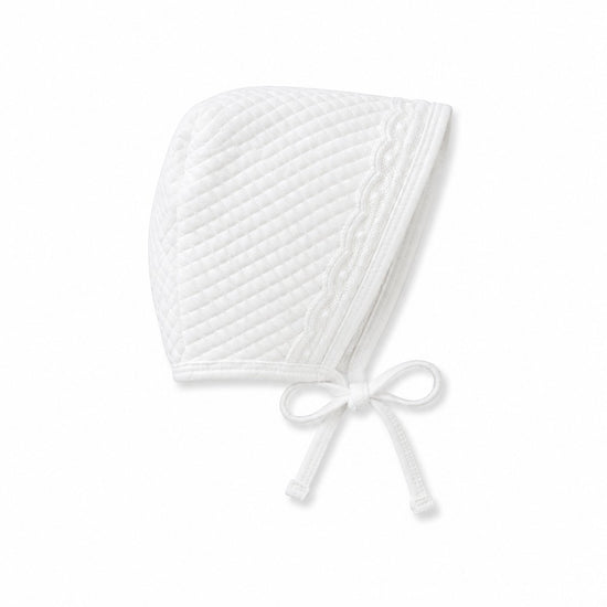 Carriage Boutique white quilted baby bonnet with delicate lace trim and tie closure for a traditional bris outfit.