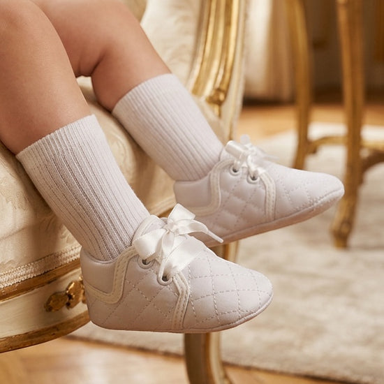 Carriage Boutique white quilted baby boy christening shoes with satin ribbon laces worn with white ribbed socks