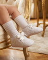 Carriage Boutique white quilted baby boy christening shoes with satin ribbon laces worn with white ribbed socks