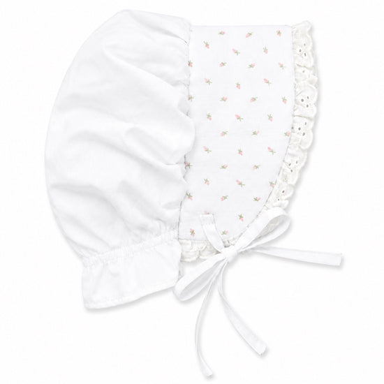 Carriage Boutique white baby bonnet with delicate pink rosebud print, lace trim, and soft fabric tie closure.