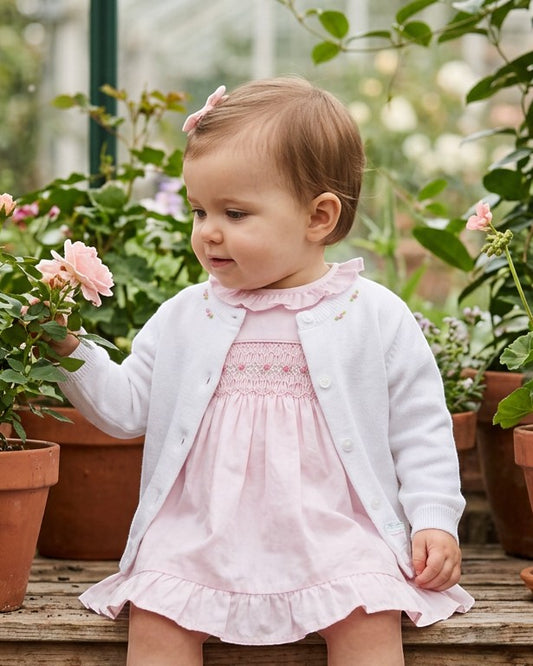 Carriage Boutique white cotton cashmere baby girl cardigan with delicate rosebud embroidery worn over a pink dress
