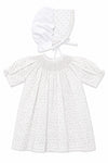 Carriage Boutique white baby girl dress with delicate rosebud print, smocked bodice, and matching lace-trimmed bonnet.
