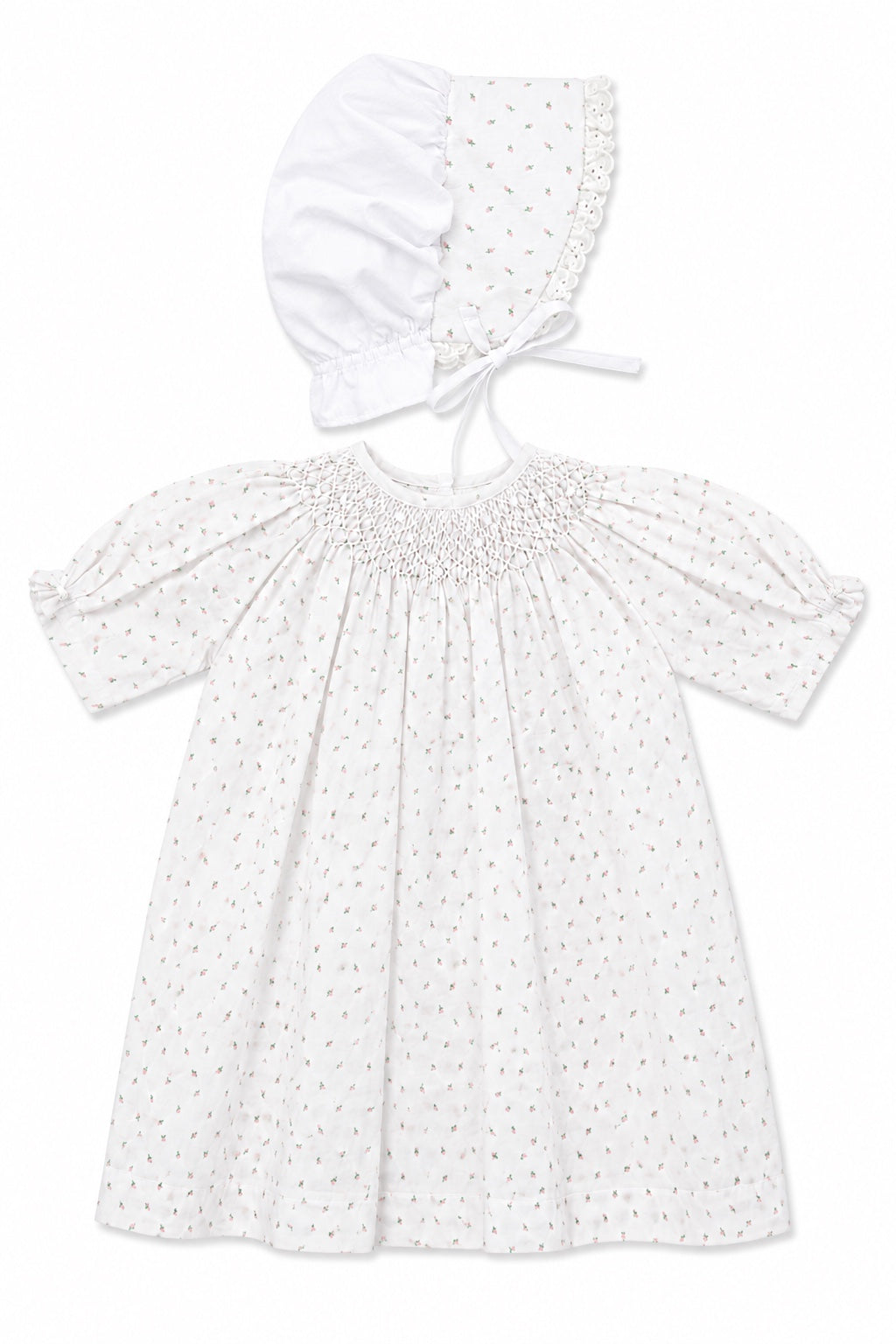 Carriage Boutique white baby girl dress with delicate rosebud print, smocked bodice, and matching lace-trimmed bonnet.