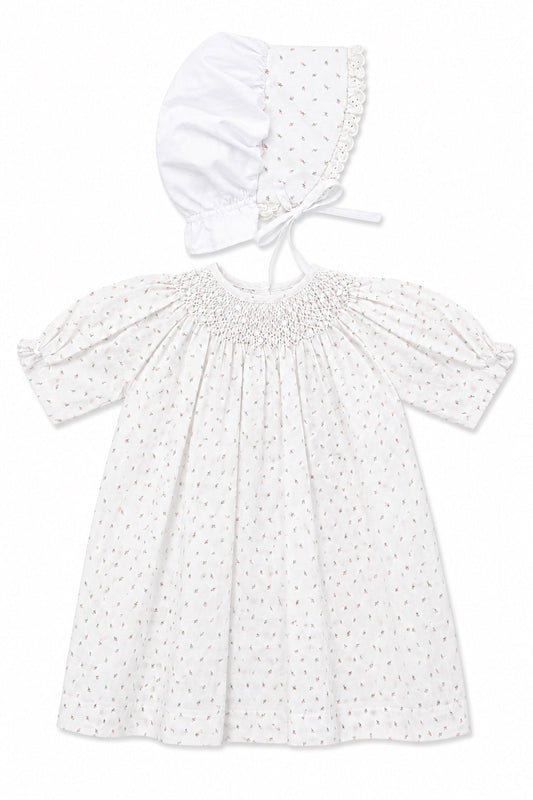 Carriage Boutique white baby girl dress with delicate rosebud print, smocked bodice, and matching lace-trimmed bonnet.