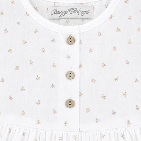 Carriage Boutique white baby dress with delicate rosebud floral print and three rustic wooden buttons on the bodice.