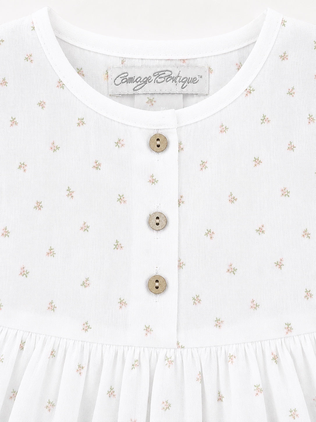 Carriage Boutique white baby dress with delicate rosebud floral print and three rustic wooden buttons on the bodice.