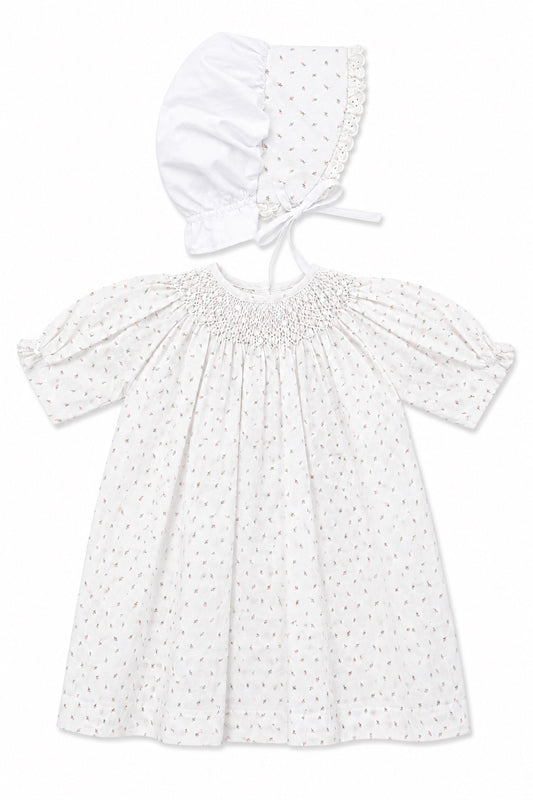 Carriage Boutique white newborn girl dress with delicate rosebud print, smocked bodice, and matching lace-trim bonnet.