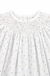 Carriage Boutique white baby girl dress featuring delicate pink rosebud print and intricate hand-smocked bodice detail.