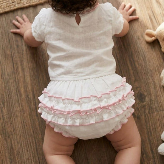 Carriage Boutique baby girl white cotton diaper cover with delicate pink ruffled trim worn by a crawling infant