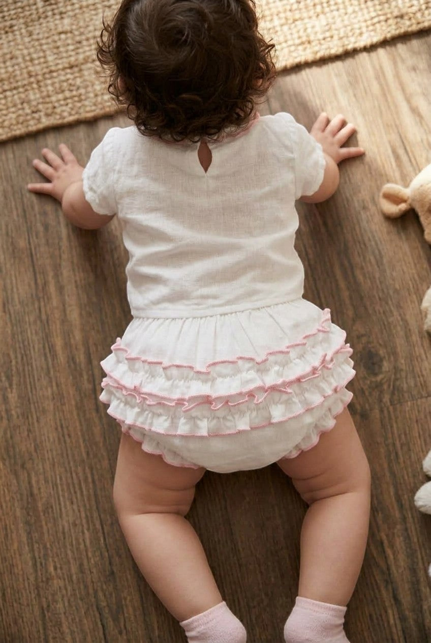 Carriage Boutique baby girl white cotton diaper cover with delicate pink ruffled trim worn by a crawling infant