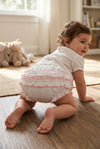Carriage Boutique baby girl white cotton diaper cover with delicate pink ruffled trim worn by a crawling toddler