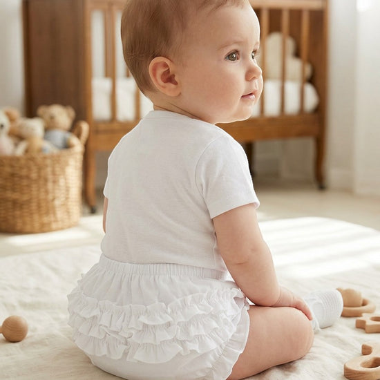 Carriage Boutique baby girl wearing white ruffled diaper cover bloomers with an elastic waistband while sitting
