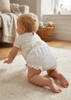 Carriage Boutique baby girl cotton diaper cover with white floral ruffles, worn by a crawling baby on a rug.