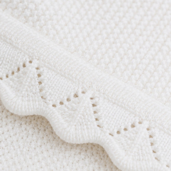 Carriage Boutique white cotton knit baby blanket featuring a delicate scalloped edge and textured diamond pattern.