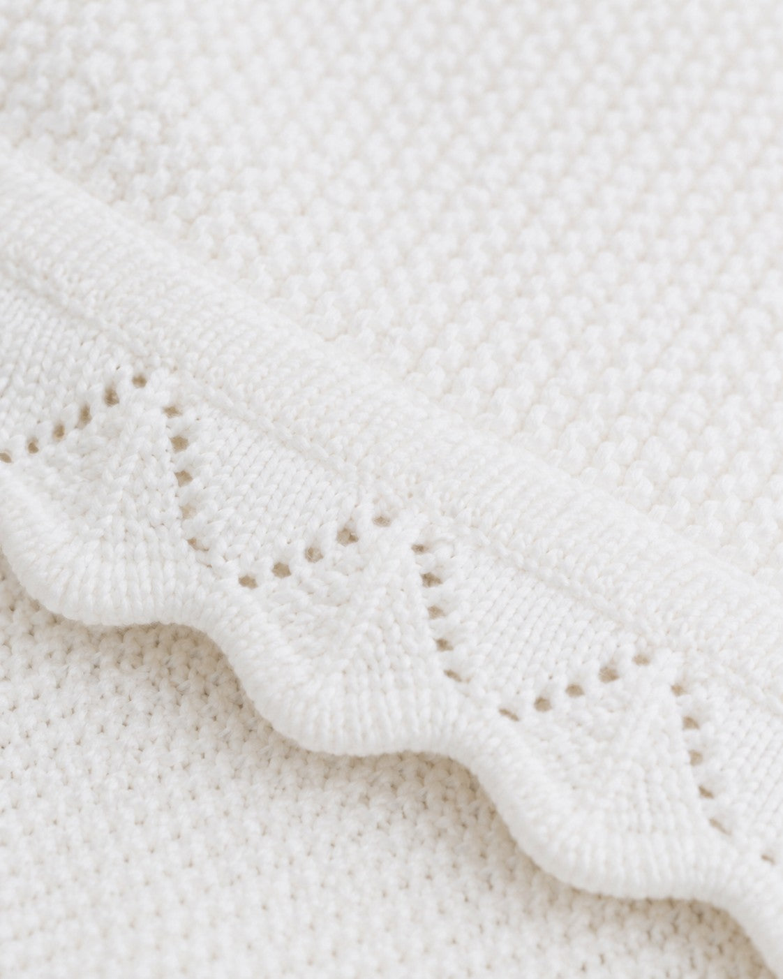Carriage Boutique white cotton knit baby blanket featuring a delicate scalloped edge and textured diamond pattern.