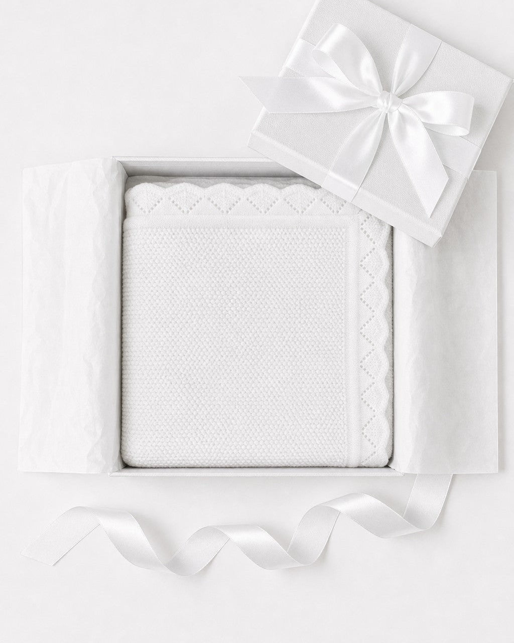 Carriage Boutique white cotton knit baby blanket with scalloped edges, presented in a gift box with a satin ribbon.