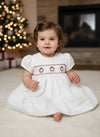 Carriage Boutique white baby dress with short sleeves, hand smocking, and red wreath embroidery for Christmas