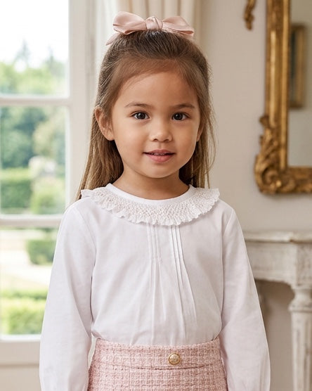Carriage Boutique white long sleeve blouse with a ruffled smocked collar worn by a young girl with a pink hair bow.