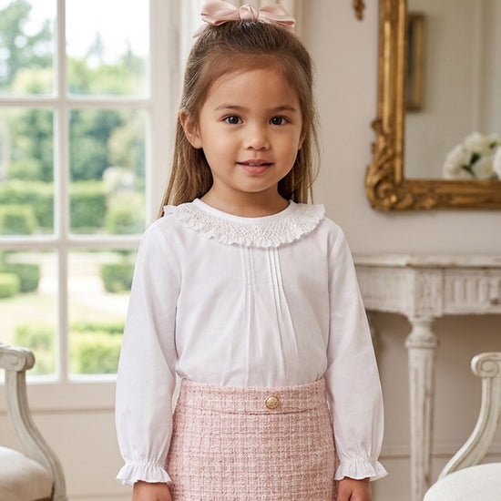 Carriage Boutique white long sleeve blouse with ruffled smocked collar worn by a young girl with a pink hair bow