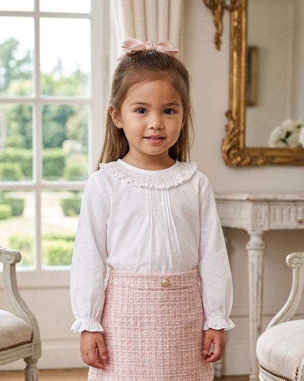 Carriage Boutique white long sleeve blouse with ruffled smocked collar worn by a young girl with a pink hair bow