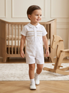 Toddler boy wearing a white Carriage Boutique hand-smocked bobby suit with shorts for a formal occasion.