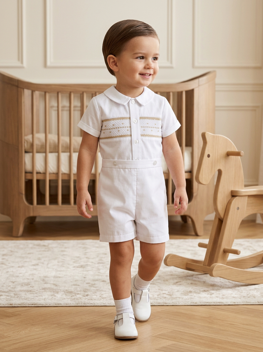 Toddler boy wearing a white Carriage Boutique hand-smocked bobby suit with shorts for a formal occasion.